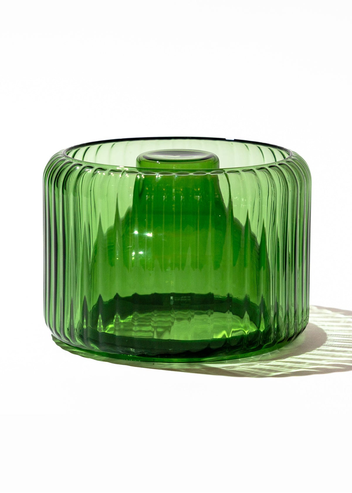 Green glass vase with ribbed texture photographed on white background