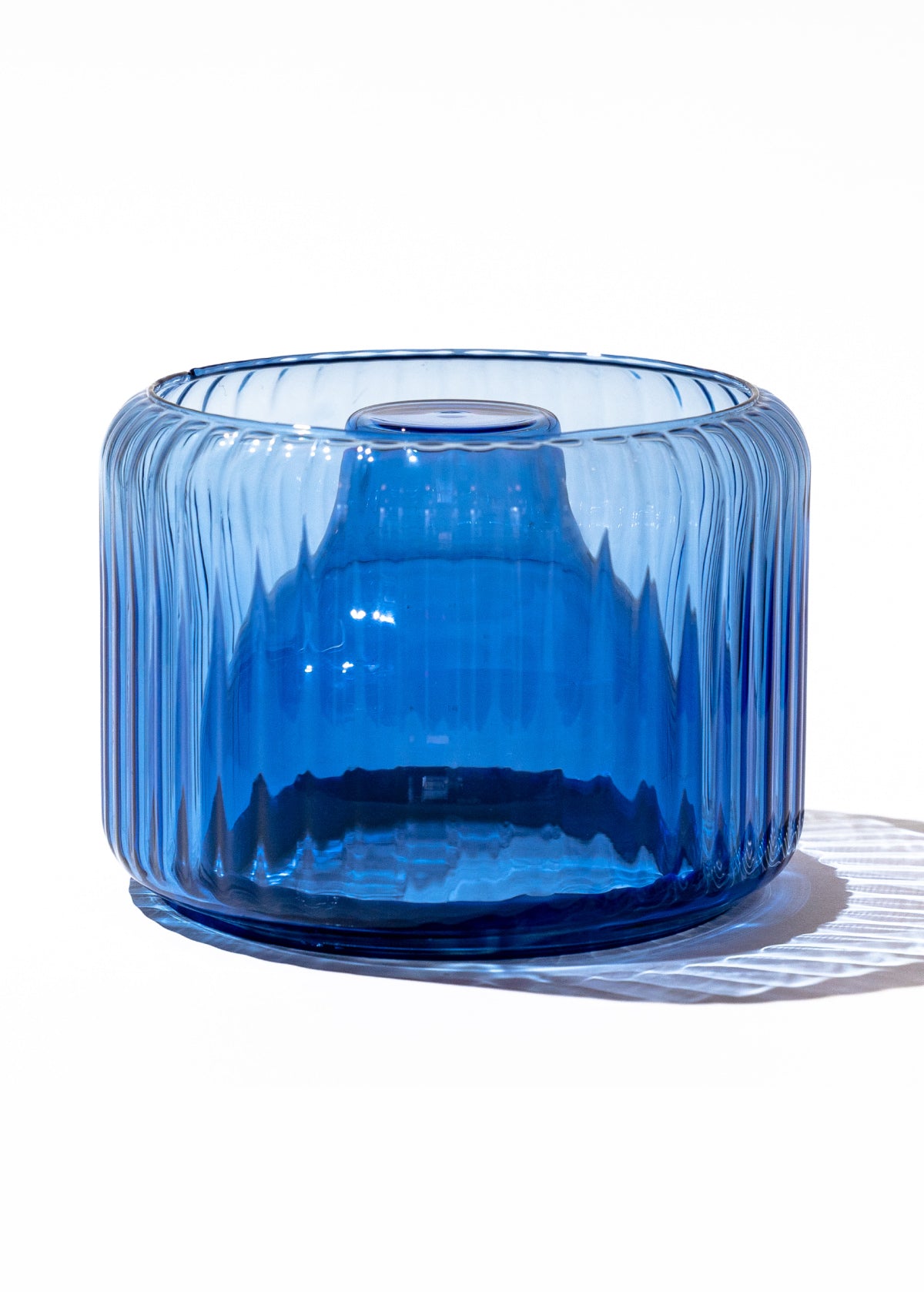 Blue glass vase with ribbed texture photographed on white background