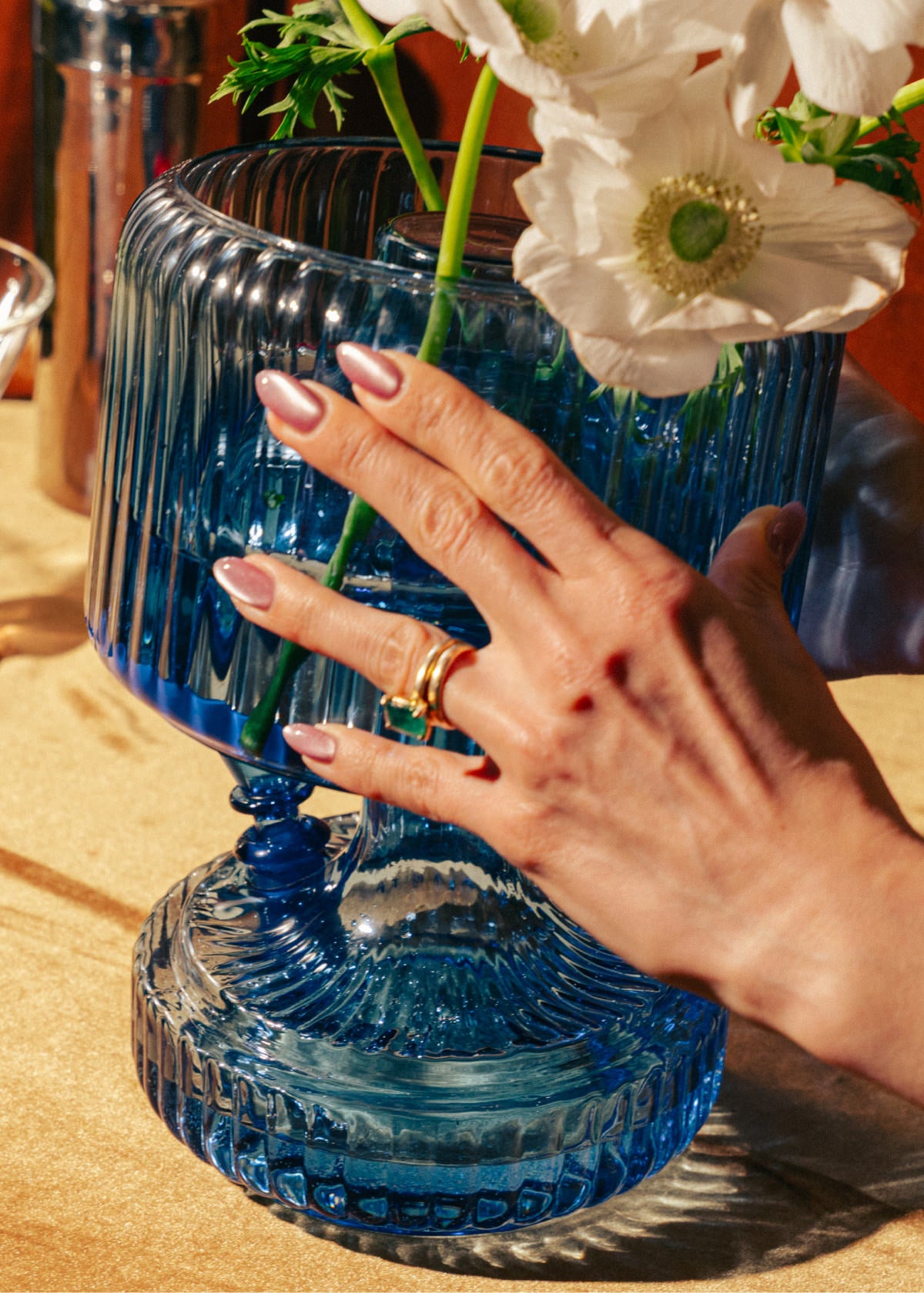 Hand placing ribbed blue flower vase top onto matching glass bong base 